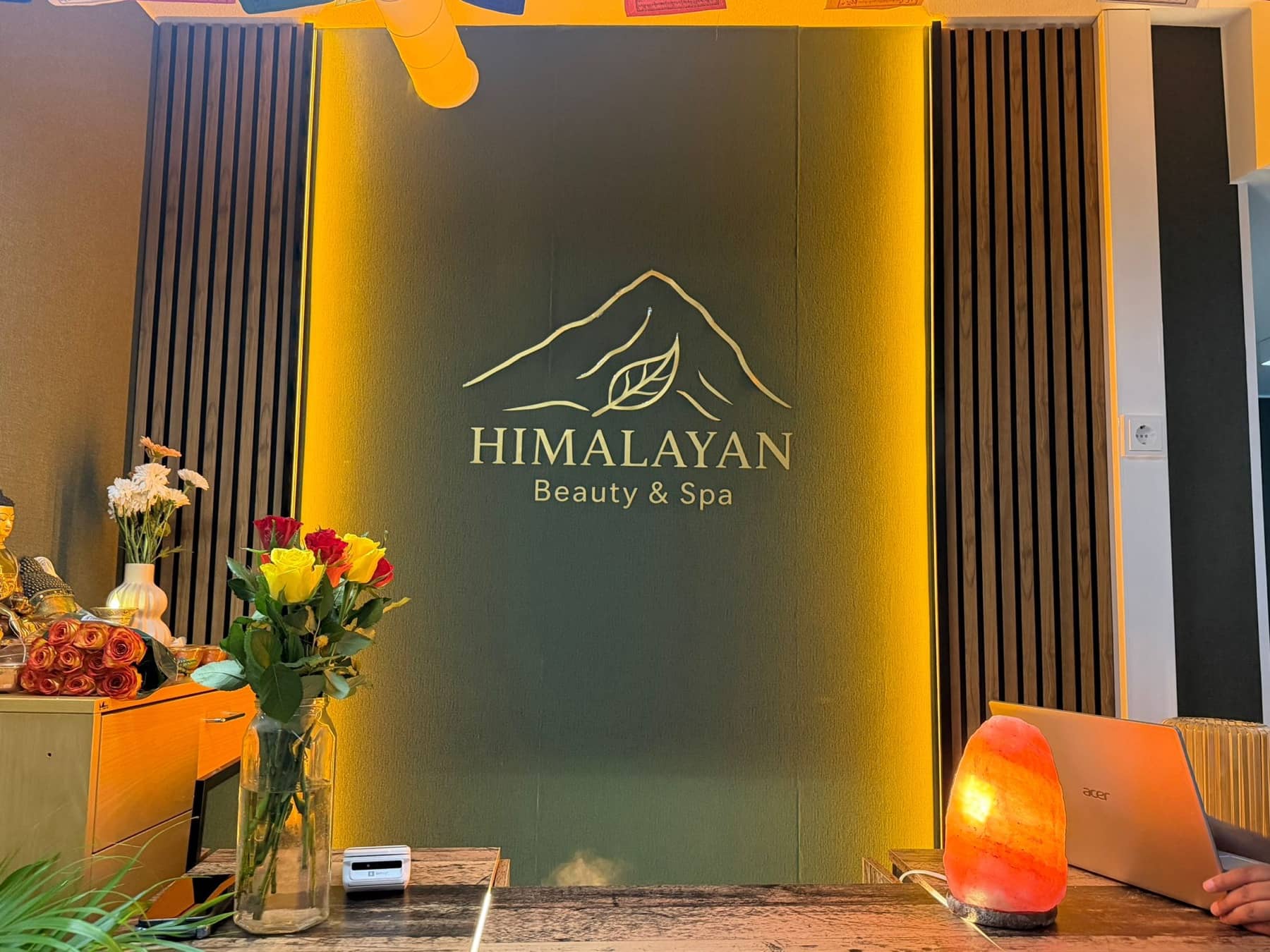 Himalayan Beauty & Span vastaanotto Pasilassa — kultainen Himalaja-logoseinä kukkineen ja pehmeine valaistuksineen