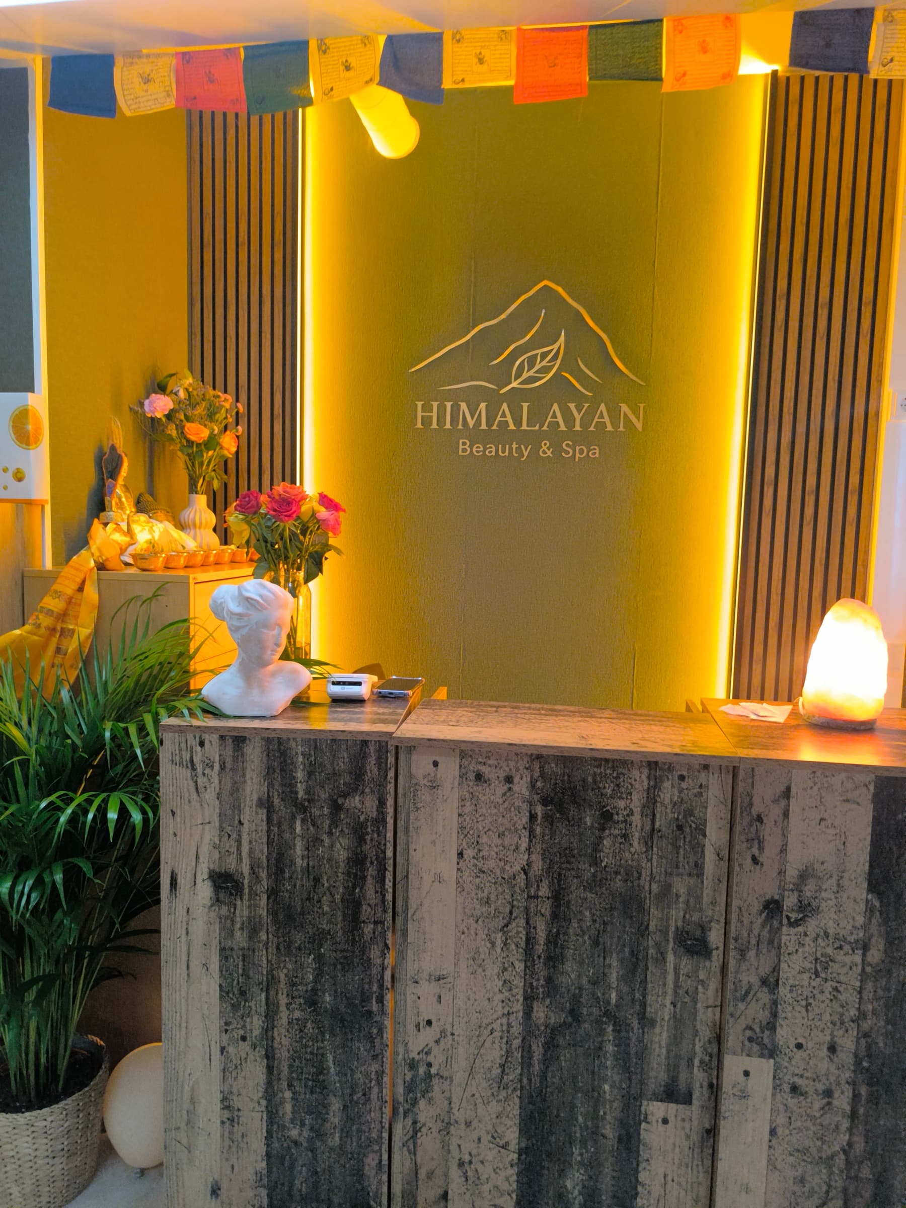 Kultainen Himalayan-logoseinä vastaanotossa, kukkien ja suolalampun kera